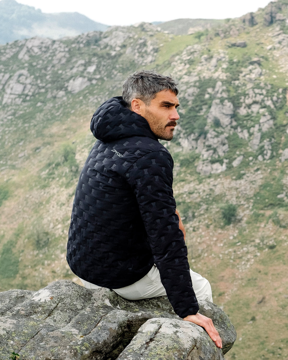 Man sitting on a rock with a mountainous landscape in the background