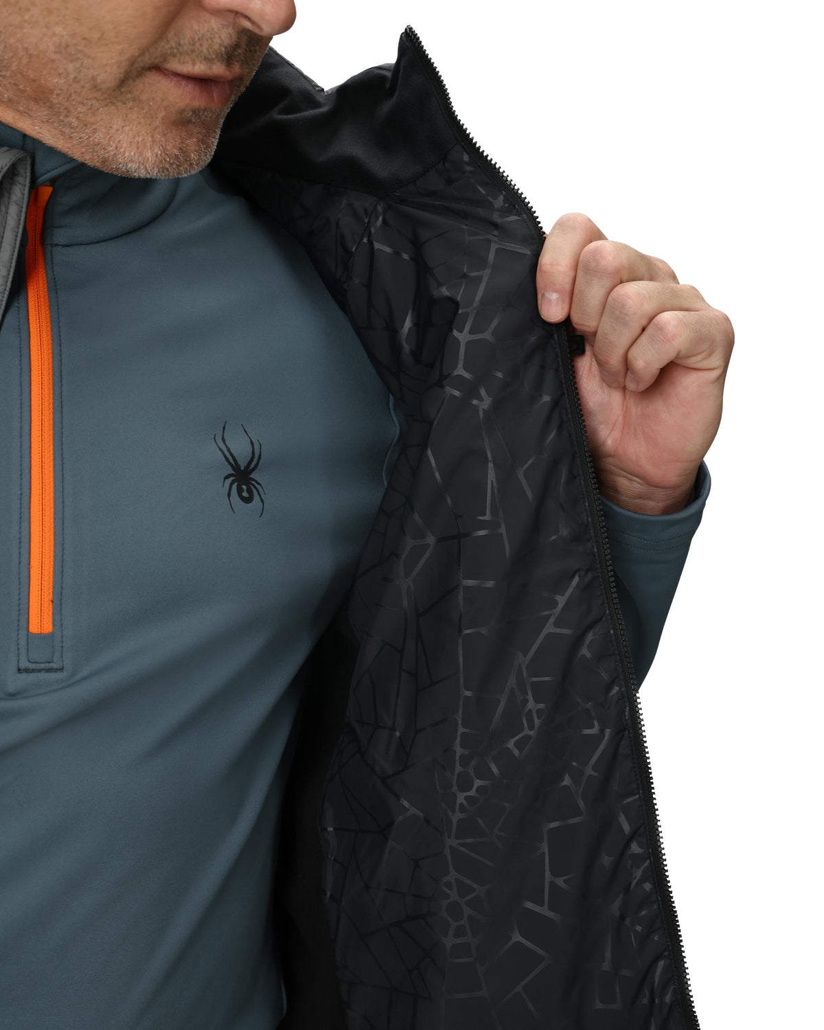 Person wearing a gray pullover with an orange zipper and black patterned jacket