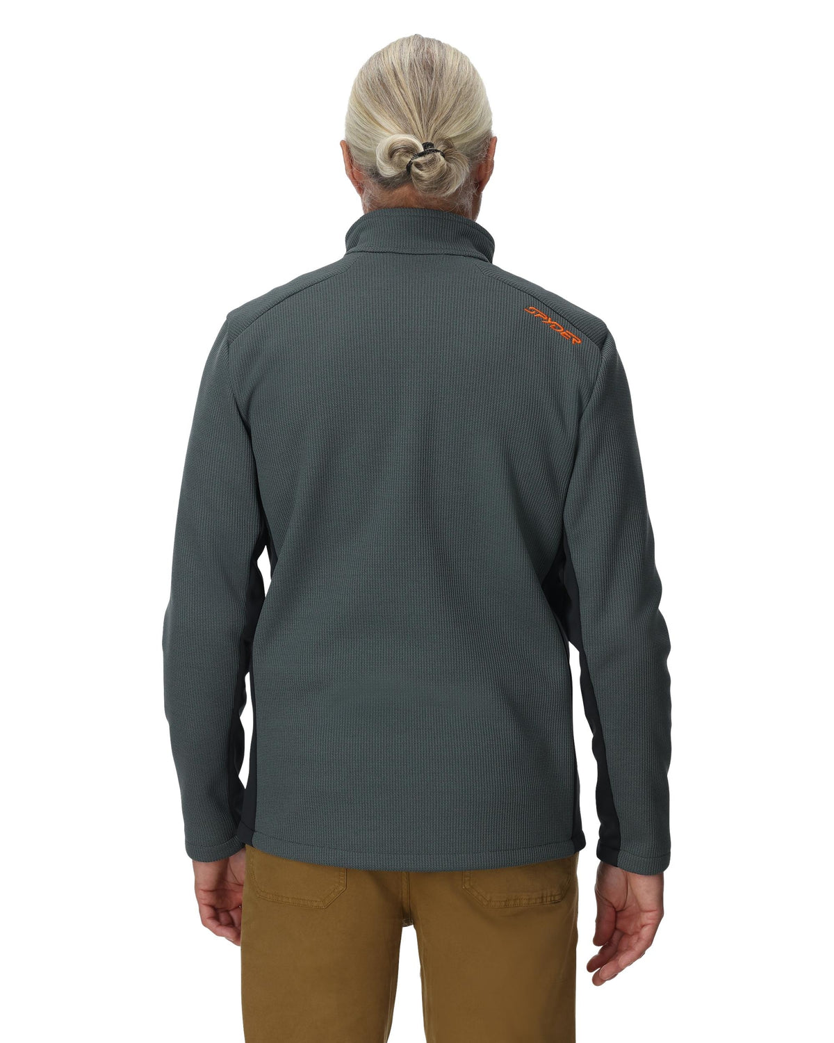 Person wearing a gray jacket with a logo on the back, standing against a white background