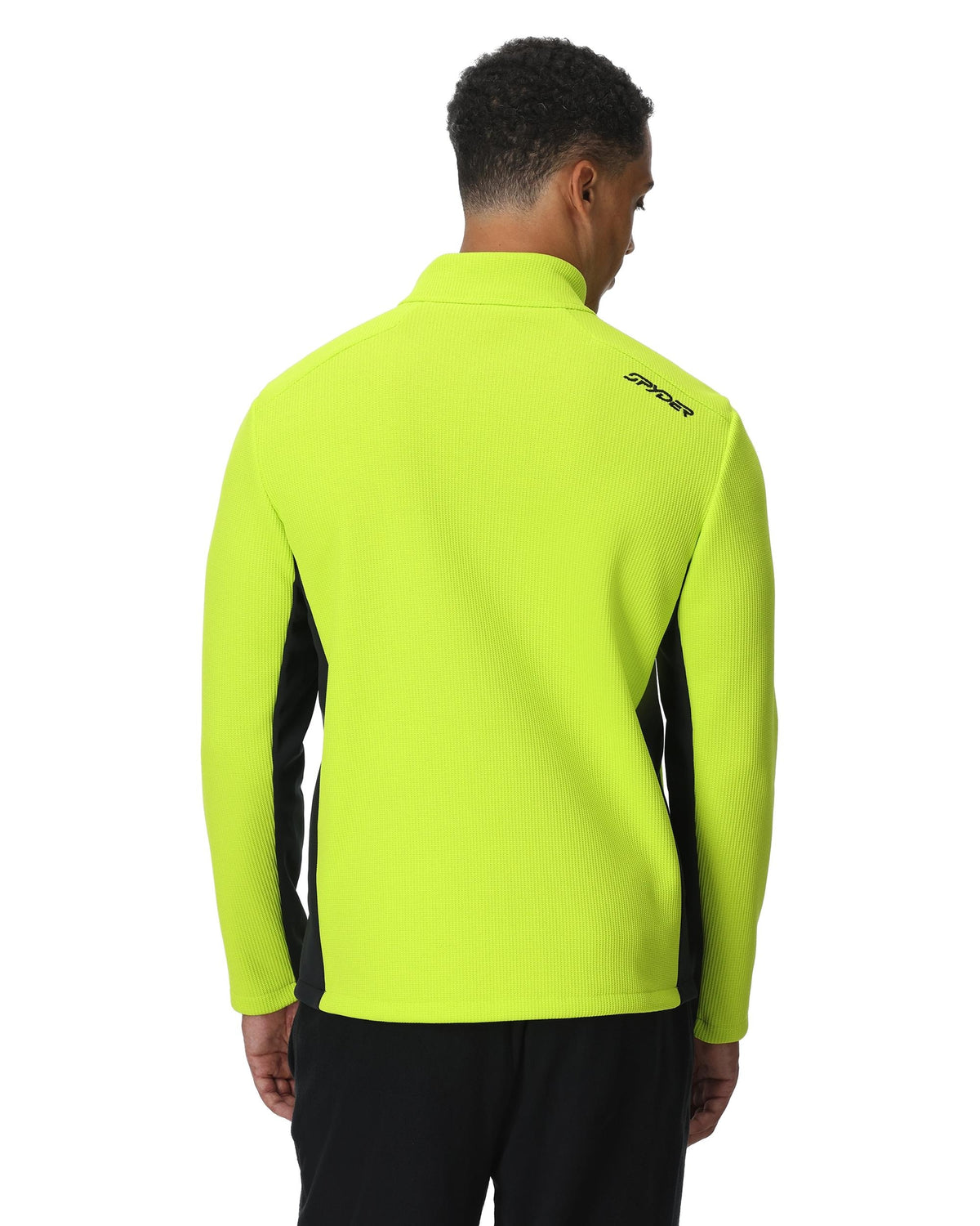 Person wearing a bright yellow jacket with a brand logo on the back, standing against a white background.