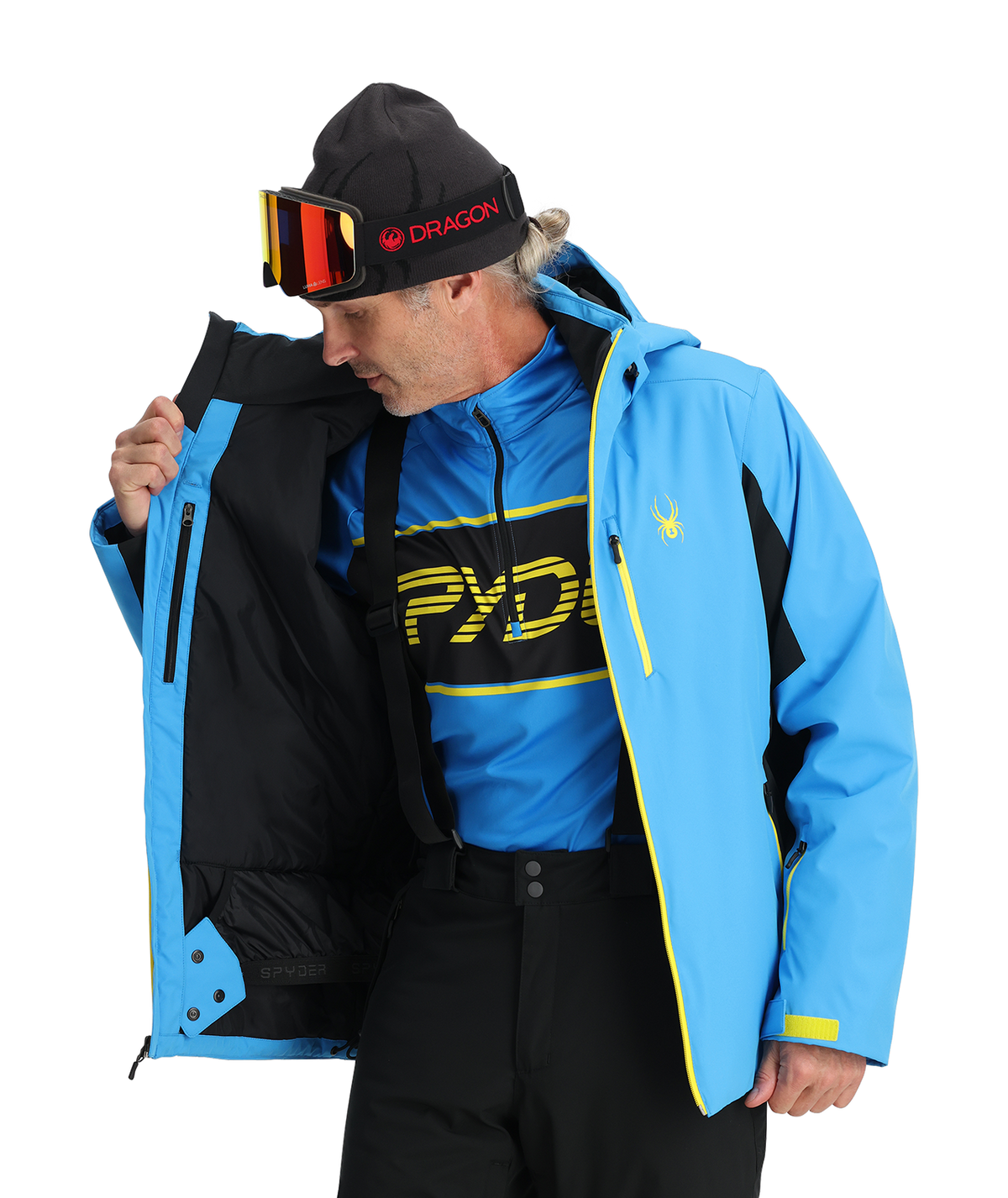 Person wearing a blue and black jacket with 'Pyrenees' branding, holding a black jacket.