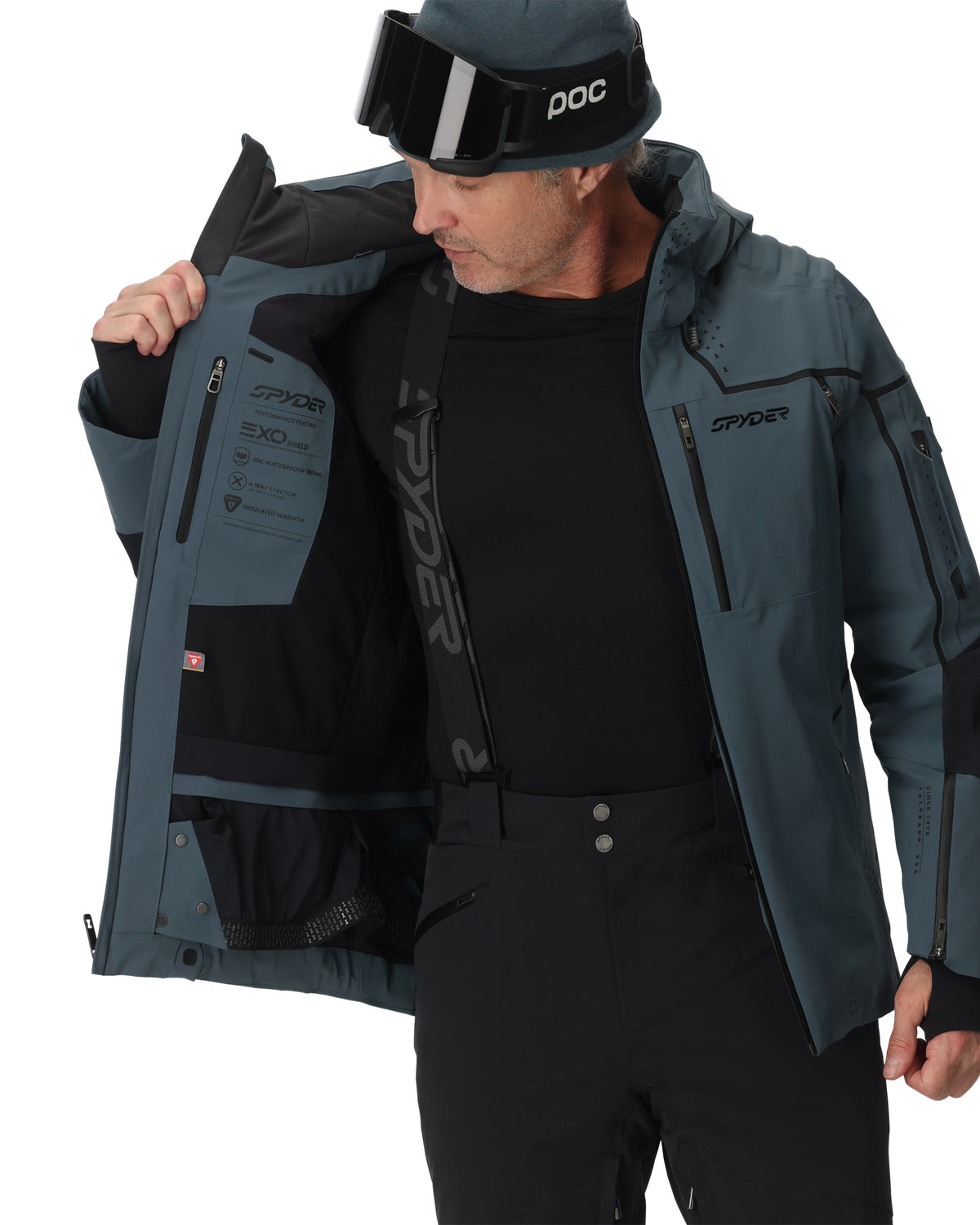 Person wearing a gray and black jacket with Spyder branding on a white background