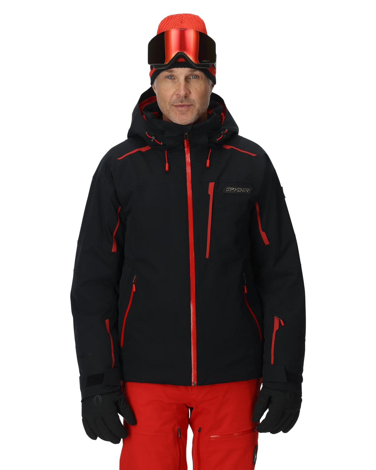 Man wearing a black and red ski jacket with goggles on a white background