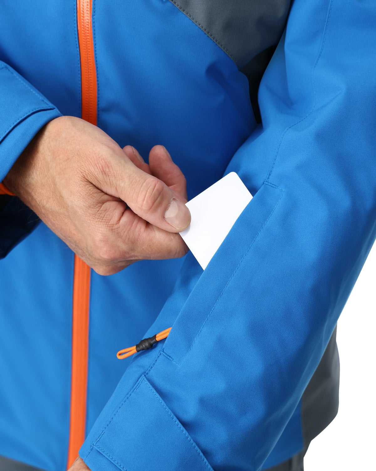 Person wearing a blue jacket with orange accents holding a white card.
