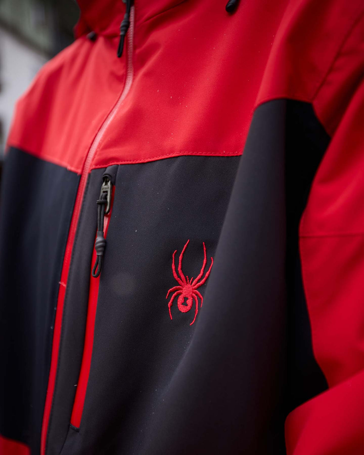 Red and black jacket with a spider logo on a blurred background