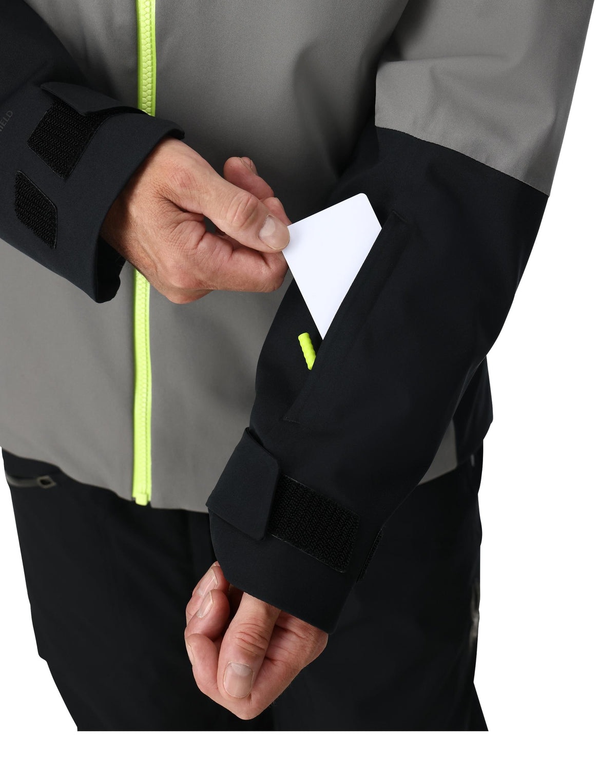 Person wearing a gray and black jacket with a white card in a pocket