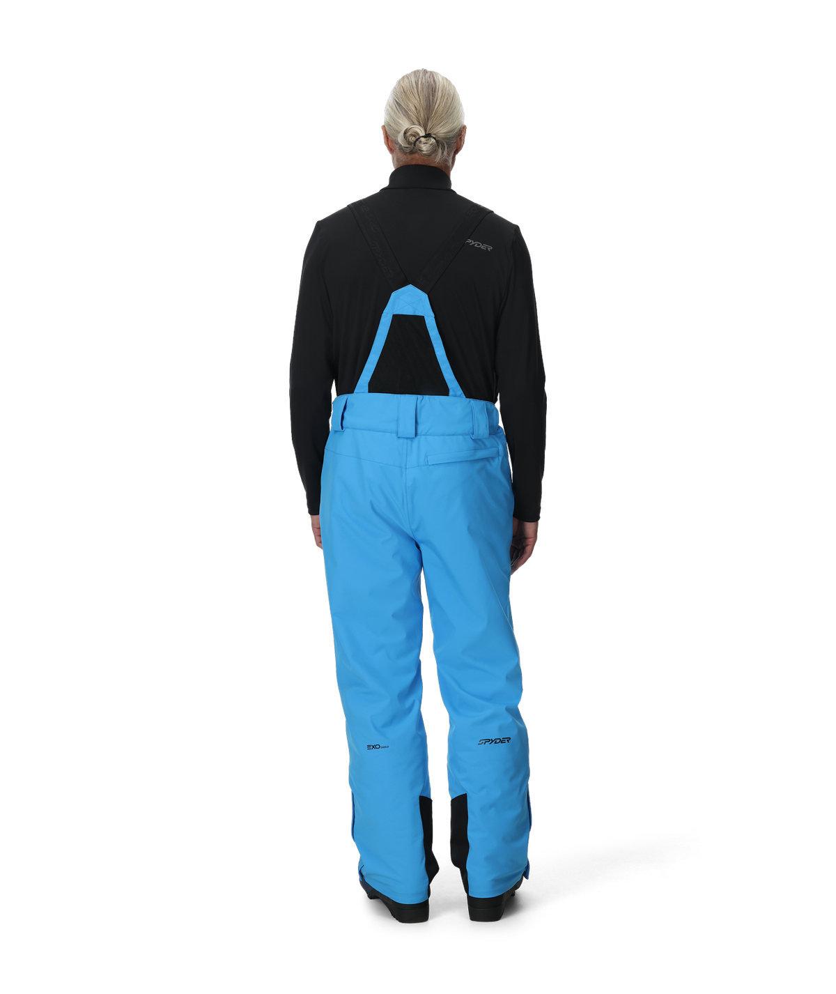 Person wearing blue snow pants with a black jacket on a white background
