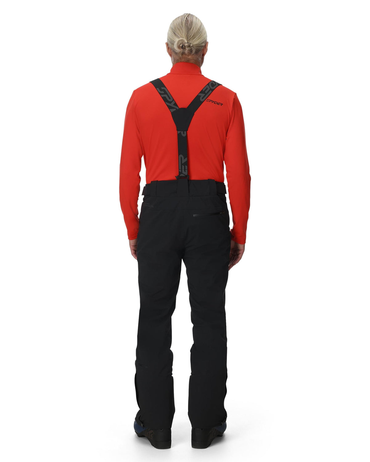 Person wearing a red top and black pants with suspenders on a white background