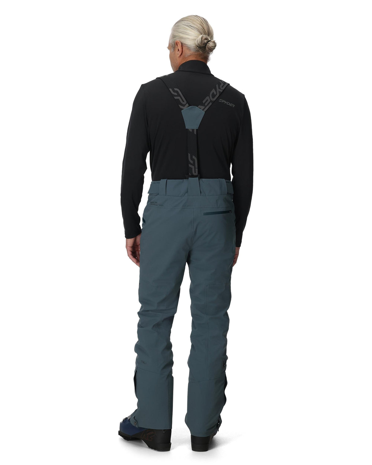 Person wearing a black jacket and blue pants on a white background