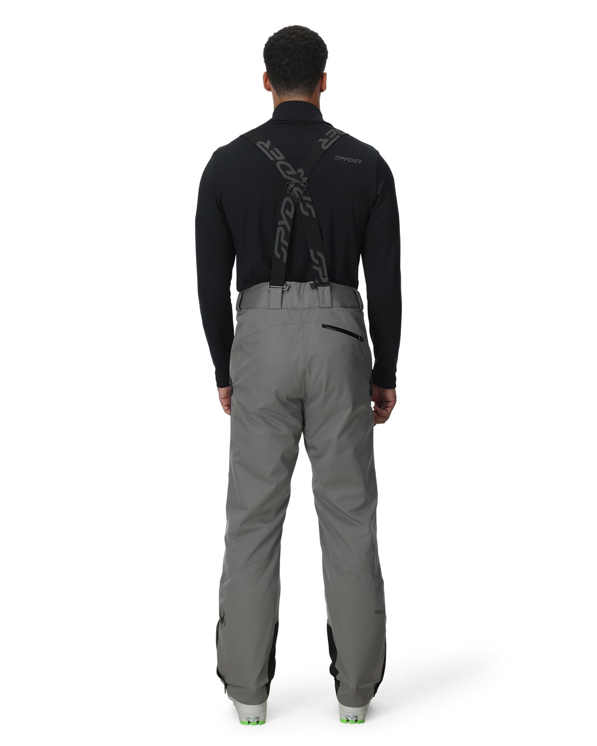 Person wearing a black jacket and gray pants on a white background