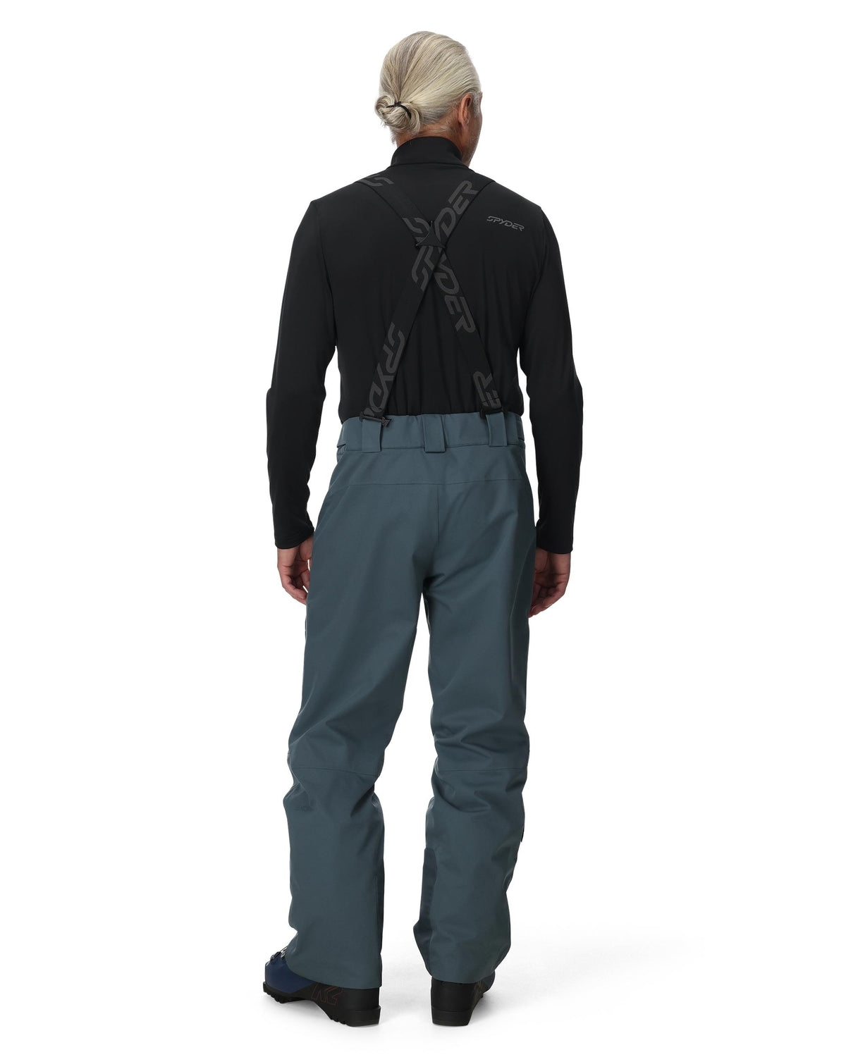 Person wearing a black jacket and gray pants on a white background