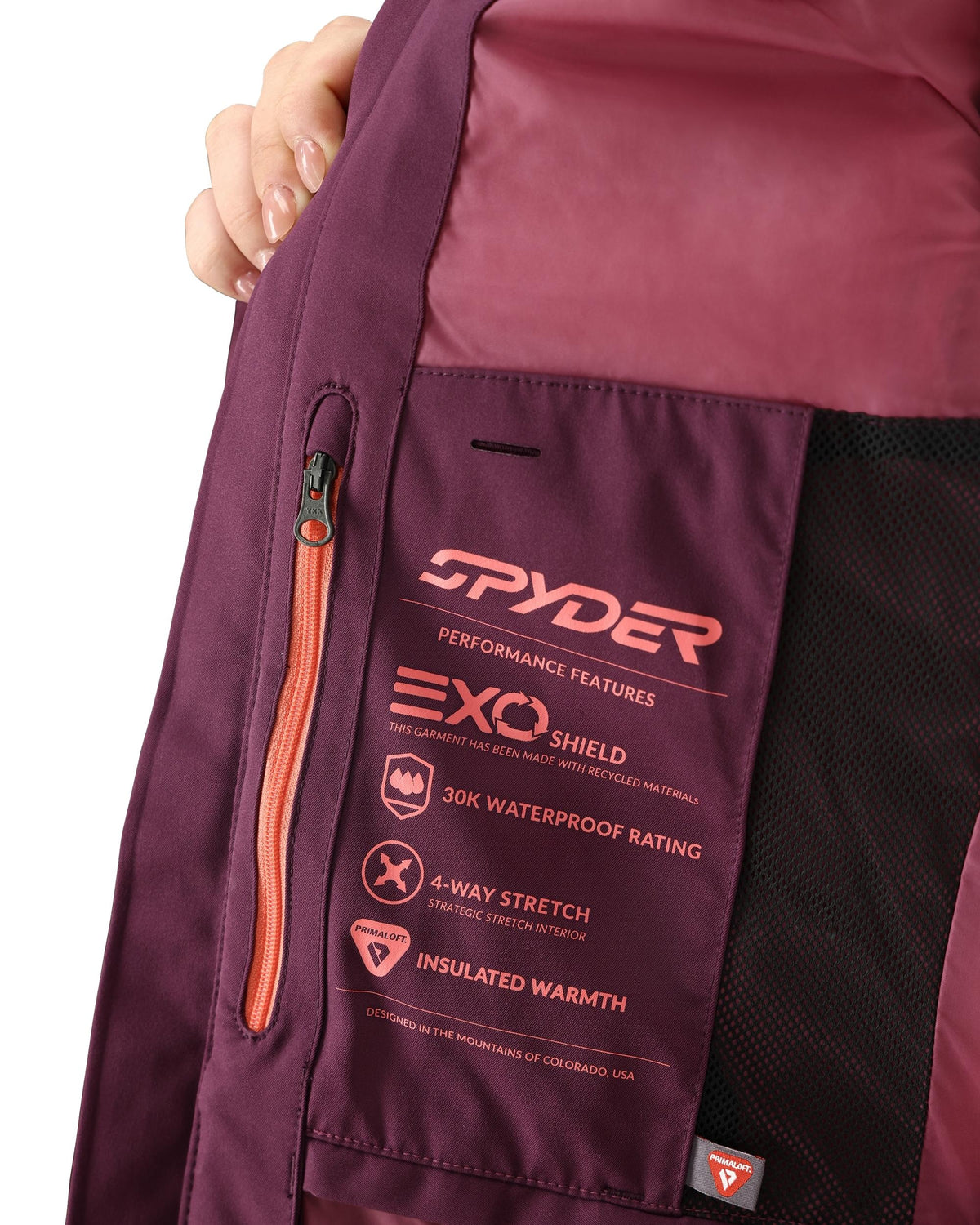 Close-up of a purple jacket with Spyder branding and feature text on a white background
