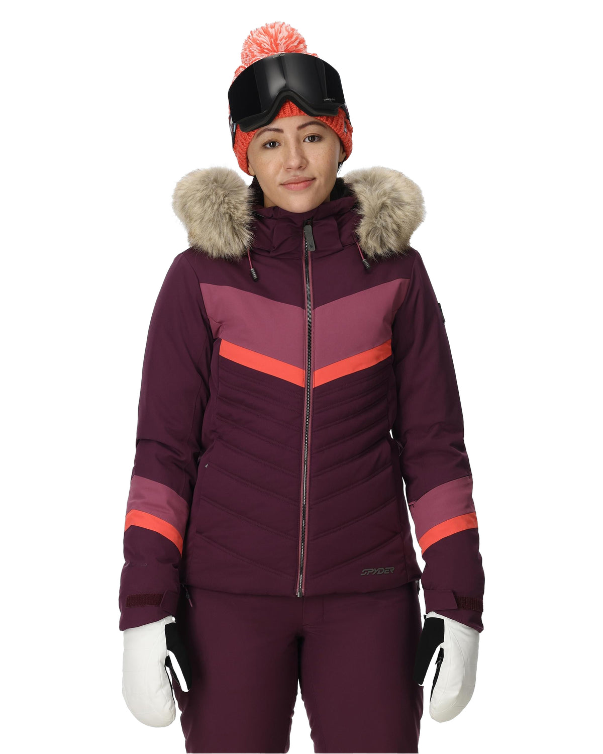 Person wearing a purple ski jacket with fur hood, goggles, and gloves on a white background