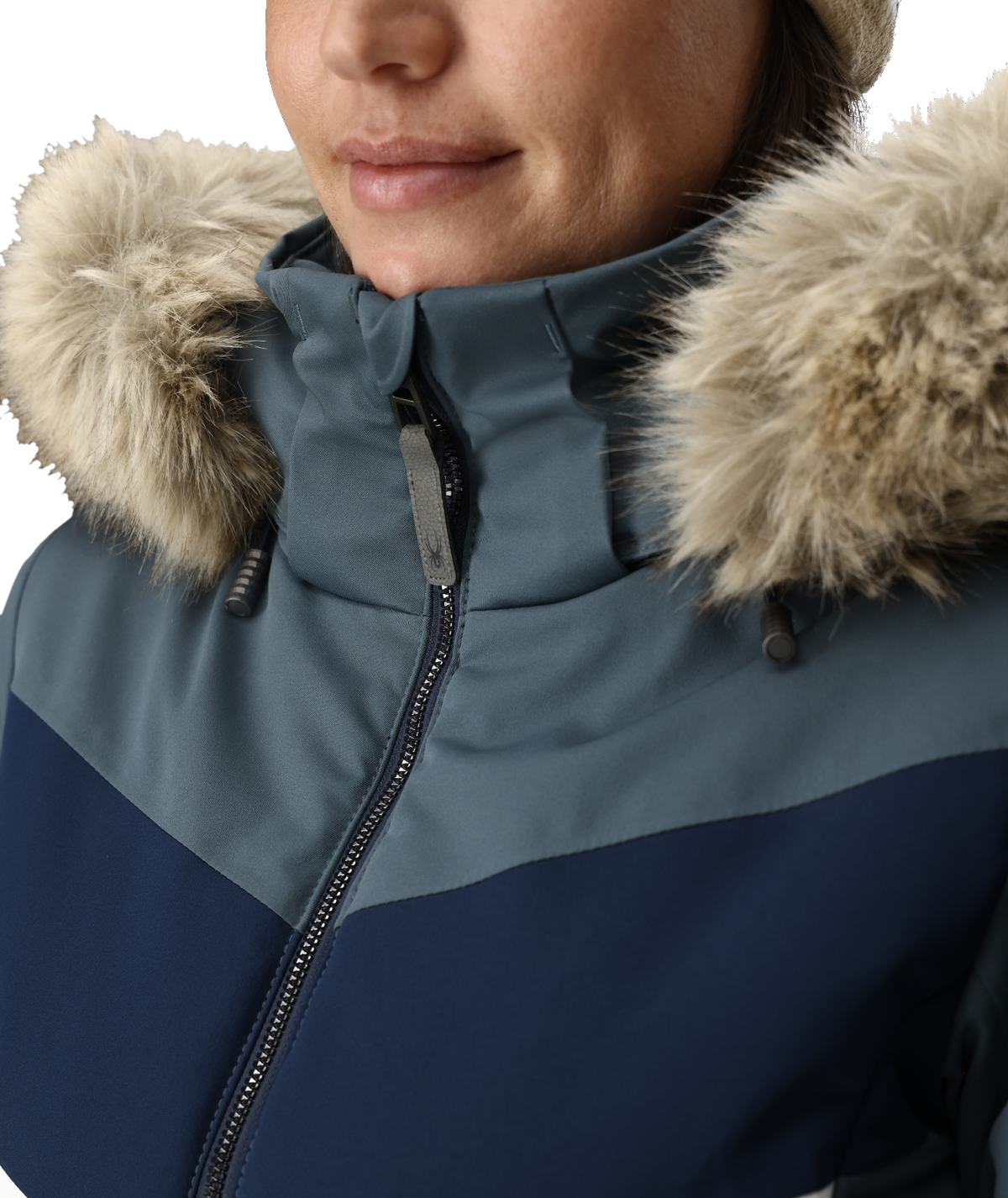Close-up of a person wearing a blue and navy winter jacket with fur-lined hood.