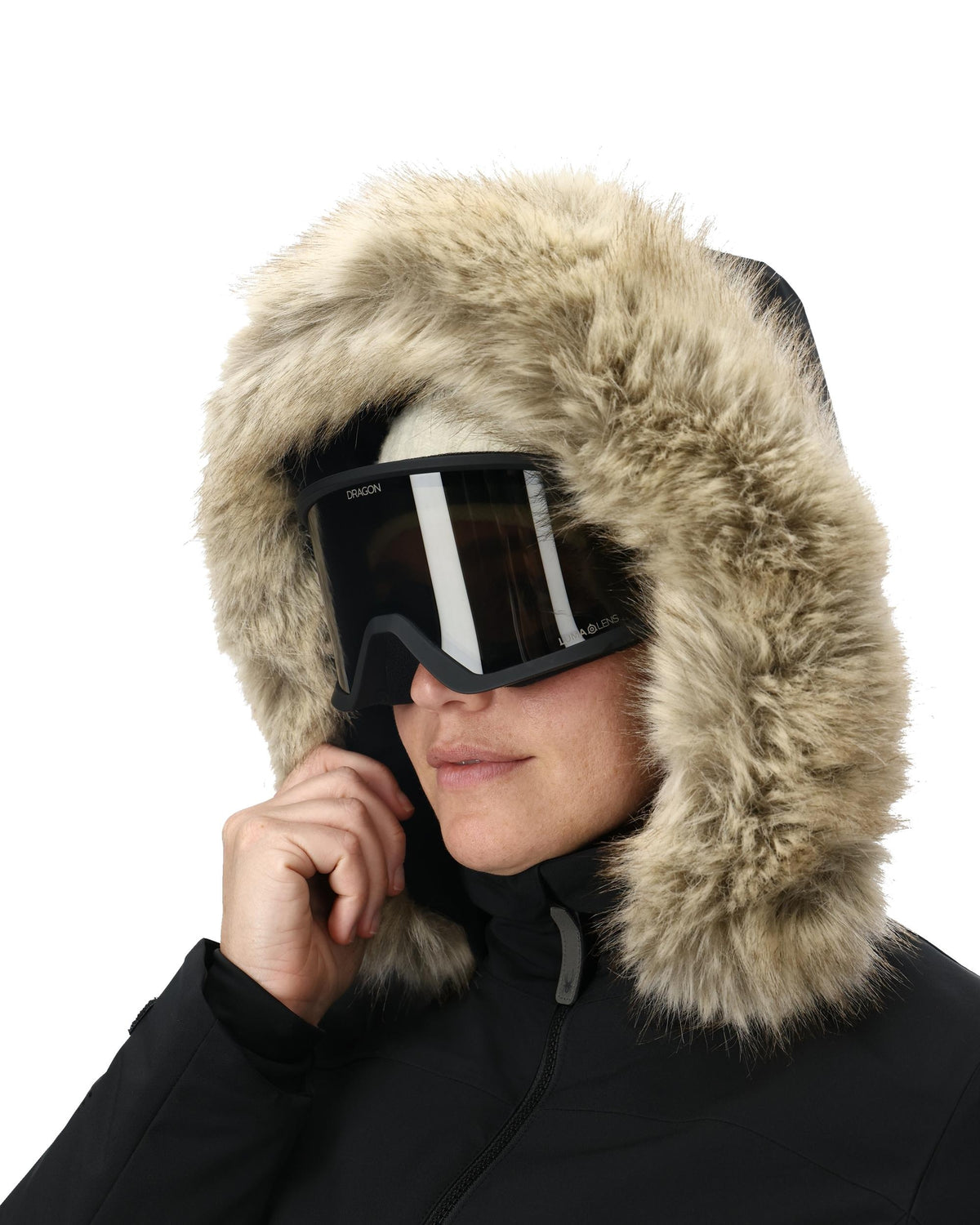 Person wearing a black coat with a fur-lined hood and goggles on a white background