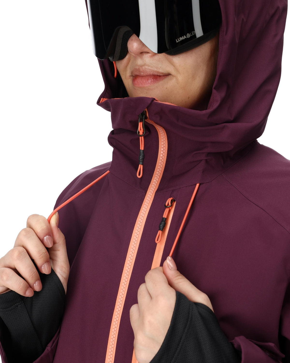Person wearing a maroon jacket with orange zipper and goggles on a white background