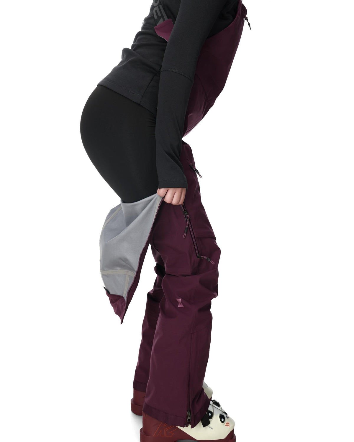 Person wearing a black jacket and maroon pants on a white background