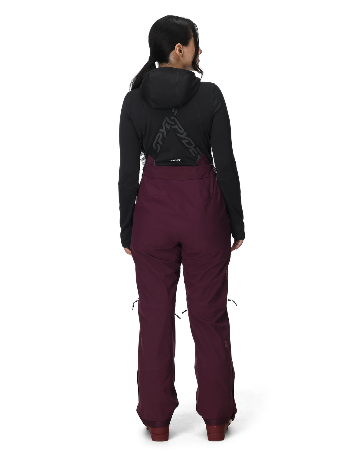 Person wearing a black jacket and maroon pants on a white background