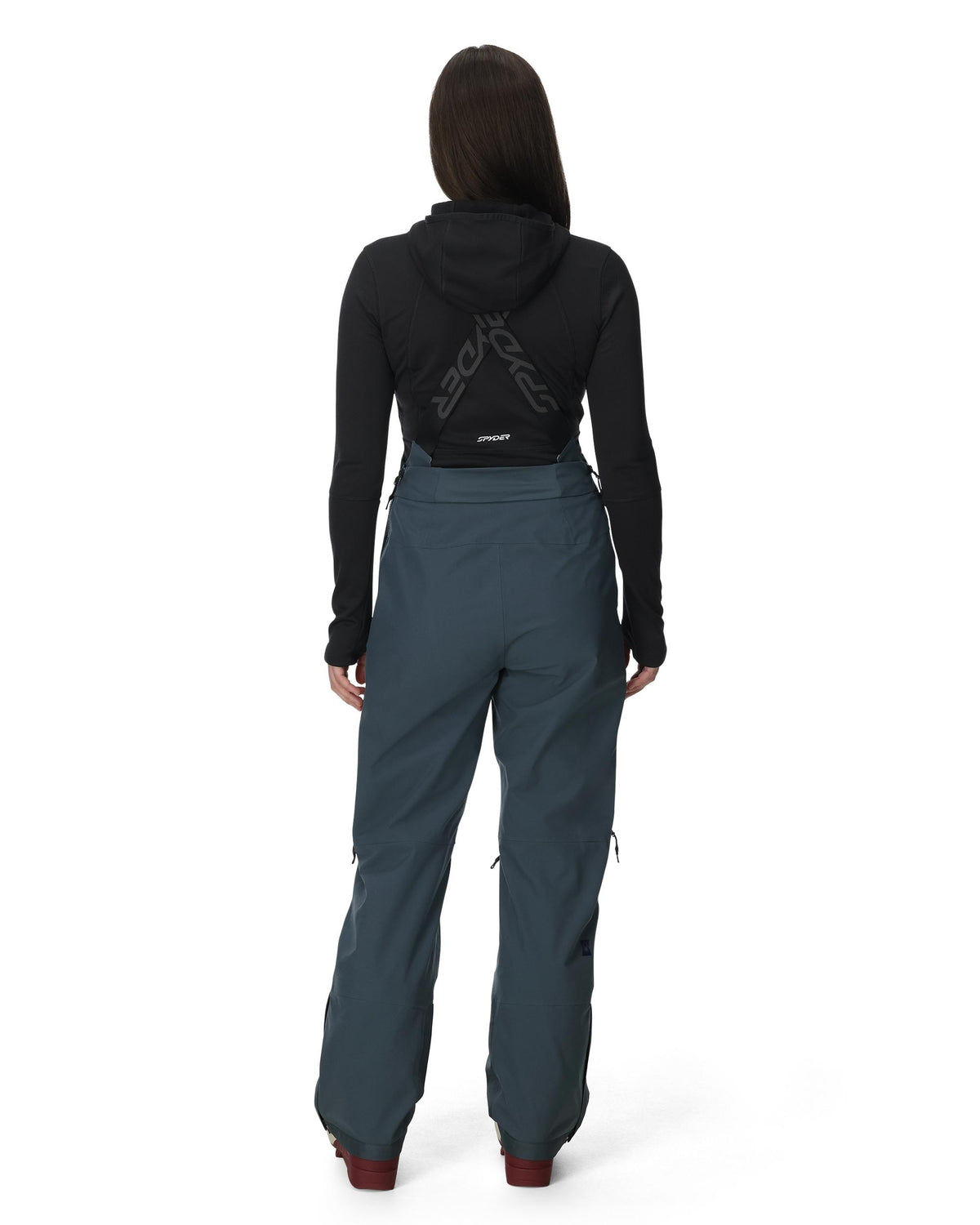 Person wearing a black hoodie and teal pants on a white background