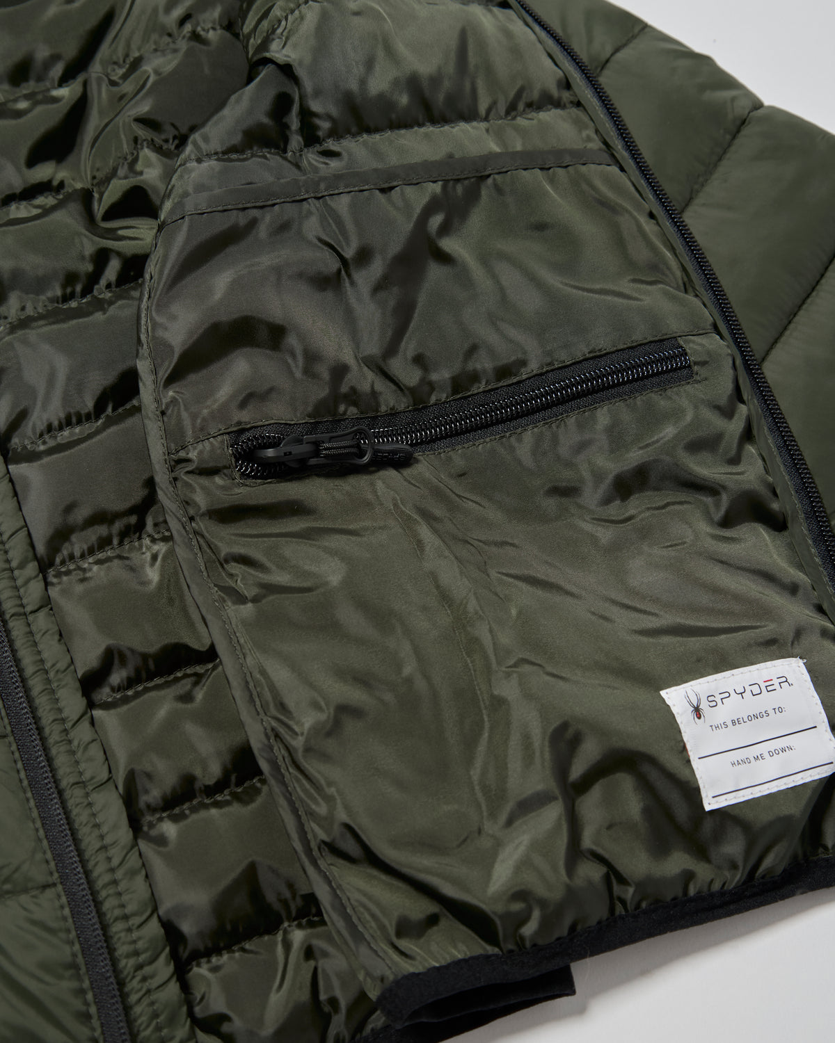 Close-up of a green puffer jacket with a Spyder label on a white background