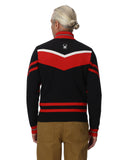 Person wearing a black and red striped sweater with a logo on the back, standing against a white background.