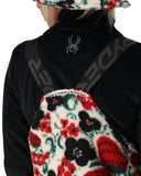 Person wearing a black jacket with a spider logo and floral-patterned gloves.