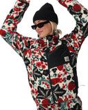 Person wearing a colorful floral-patterned outfit with a black beanie and sunglasses.