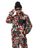 Person wearing a colorful floral-patterned outfit with a black beanie and sunglasses on a white background