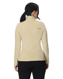 Woman wearing a beige jacket with a brand logo on the back, standing against a white background