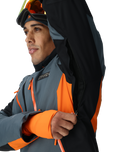 Person wearing a gray, orange, and black jacket with a brand logo on a white background