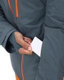 Person wearing a gray jacket with orange accents, holding a white card.