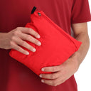 Person holding a red compression bag against a red background