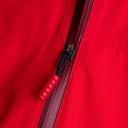 Close-up of a red jacket zipper with a red pull tab.