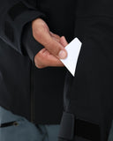Person wearing a black jacket holding a white card
