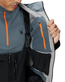 Close-up of a person wearing a gray jacket with orange zippers and a visible brand logo.