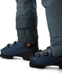 Blue slip-on shoes with black soles worn by a person in gray pants on a white background