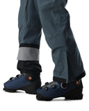 Blue ski boots with black gaiters worn with gray pants on a white background