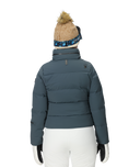 Person wearing a blue puffer jacket, white pants, and a beanie with a pom-pom on a white background