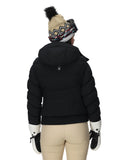 Person wearing a black puffer jacket, beige pants, and a patterned beanie on a white background