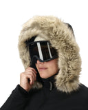 Person wearing a black coat with a fur-lined hood and goggles on a white background