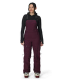 Person wearing a maroon bib overalls and black long-sleeve shirt on a white background