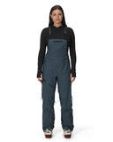 Person wearing a dark blue bib overalls on a white background