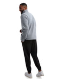 Man wearing a gray zip-up hoodie and black pants on a white background