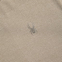 Textured beige fabric with a small spider-like object on it