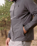 Person wearing a gray jacket with a brand logo outdoors